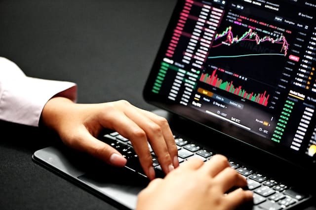 Trader revisando gráficos del mercado en tiempo real en un portátil